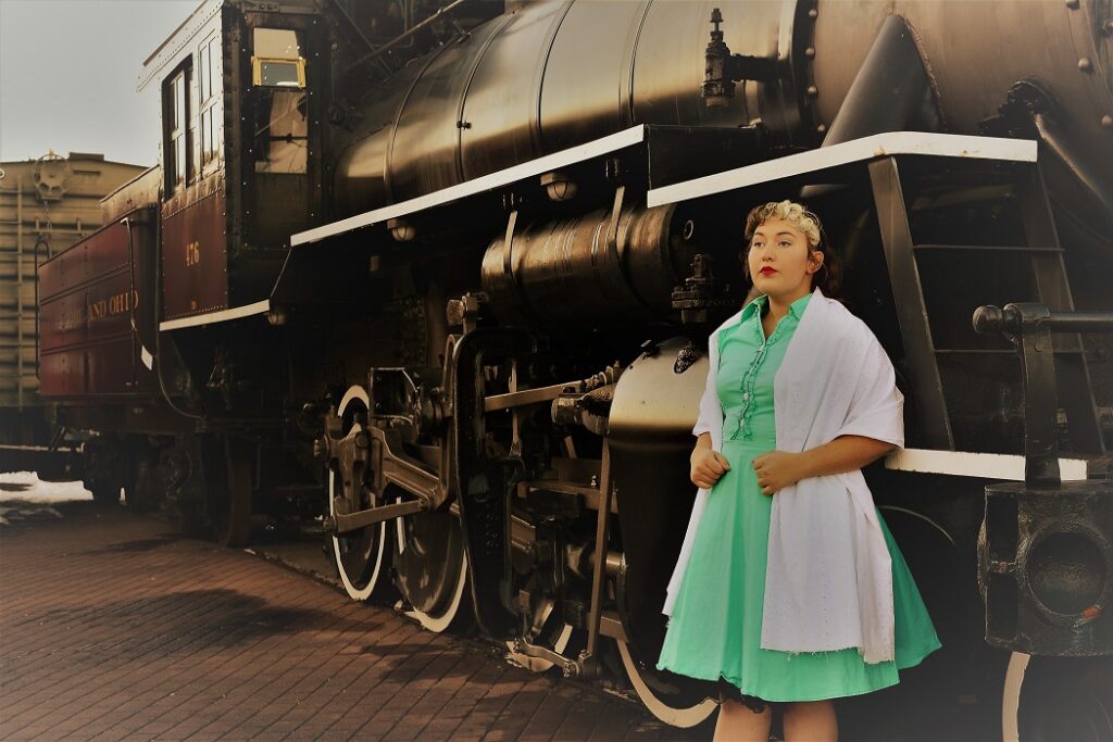 50's woman in front of a train